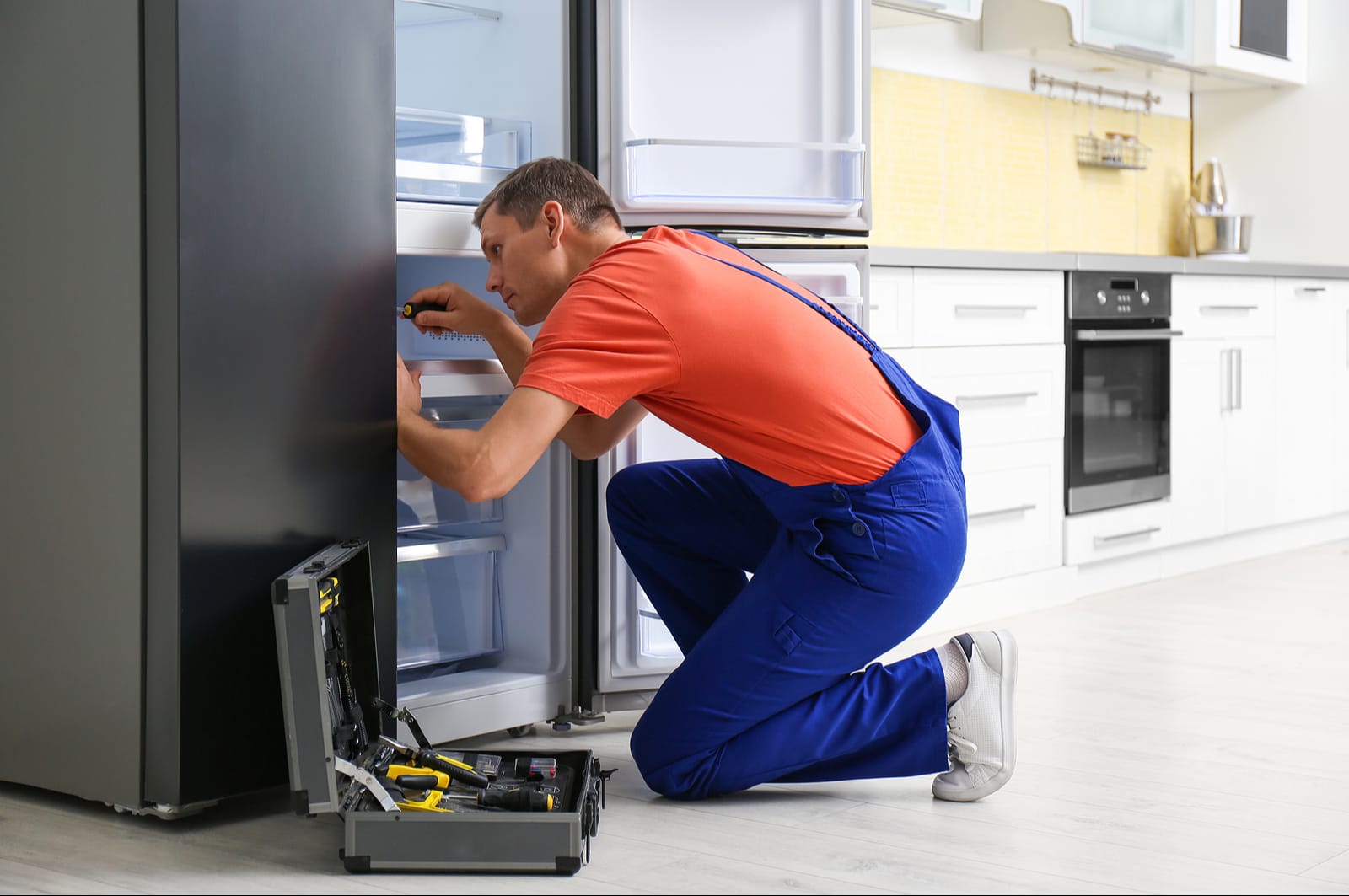 fridge repair technician repairing fridge